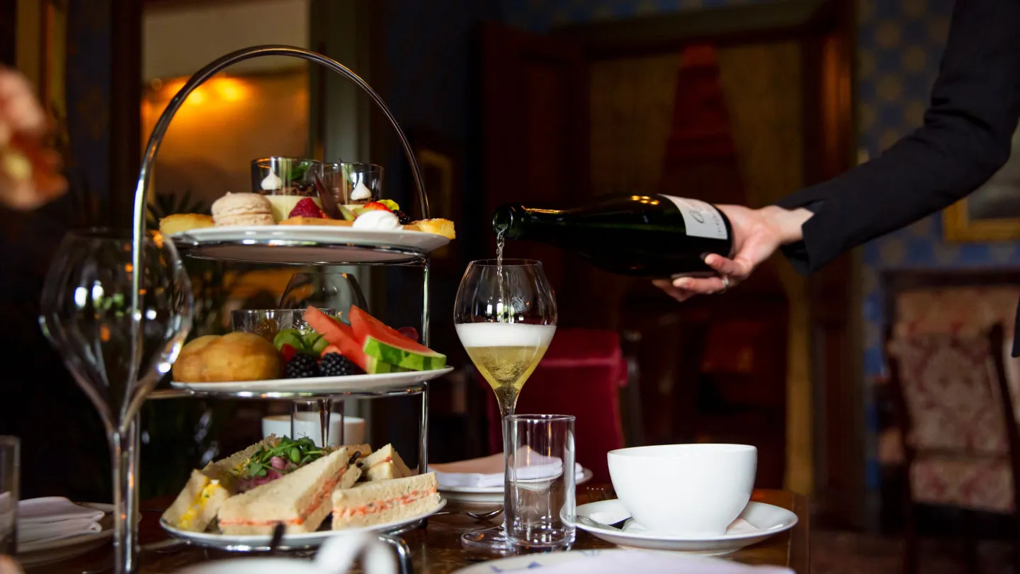 Pouring of wine next to afternoon tea.